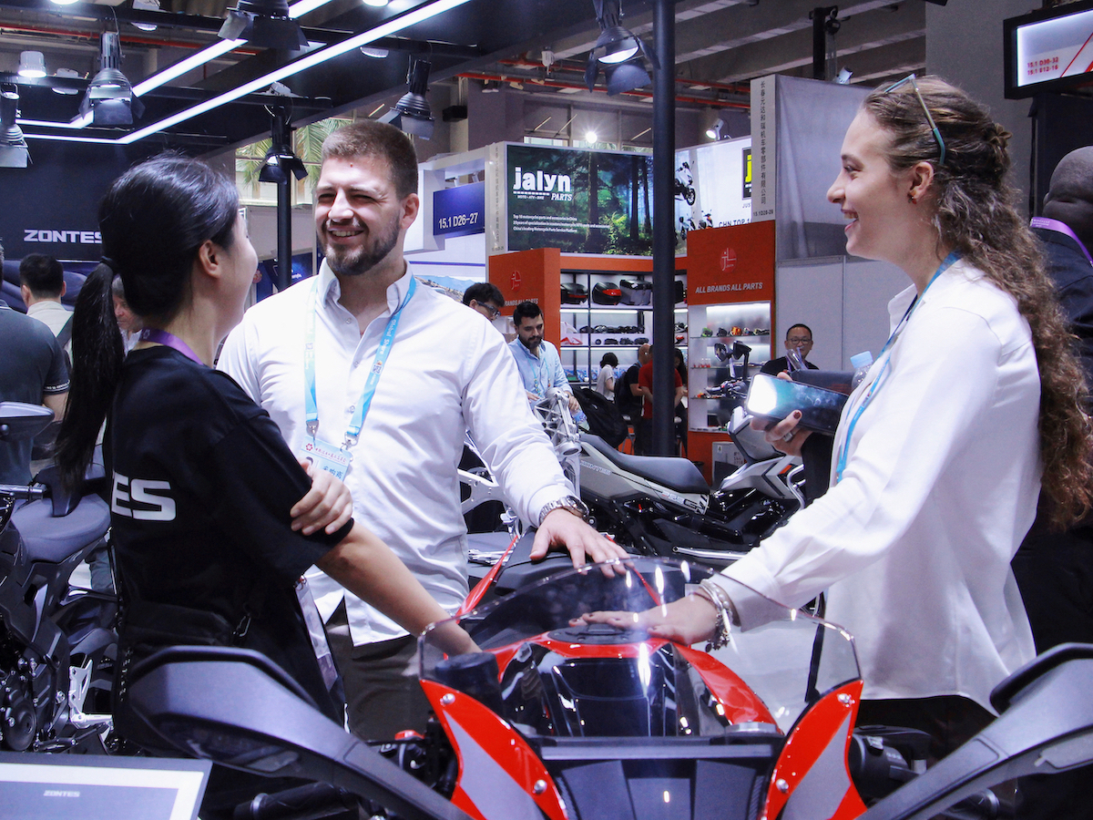 广交会现场，海外采购商向工作人员了解摩托车性能。实习生 陈琼摄
